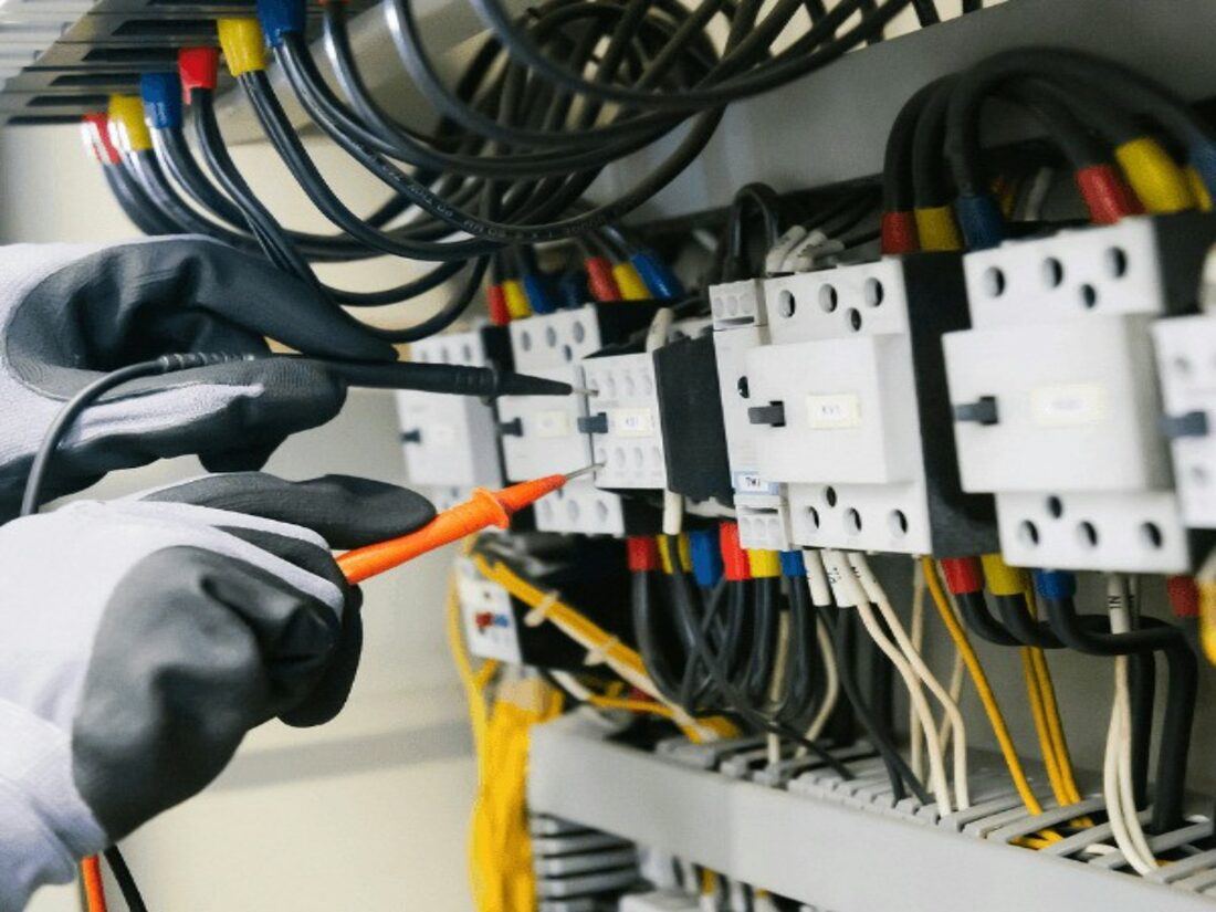An electrician testing a distribution board with a meter probe