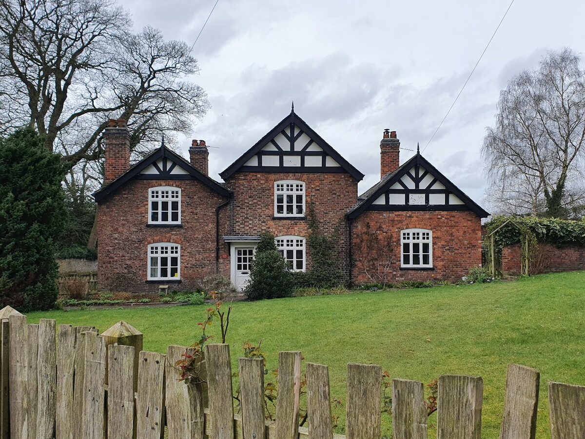Black and white timber framed house behind a fence